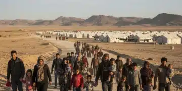 Refugee families walking towards a camp, symbolizing global displacement and humanitarian need.