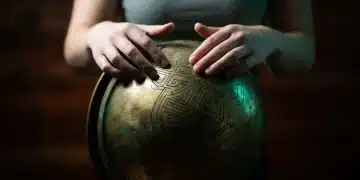 Hands tracing complex patterns on an antique brass globe, symbolizing education's unseen value in developing cognitive agility and problem-solving skills.